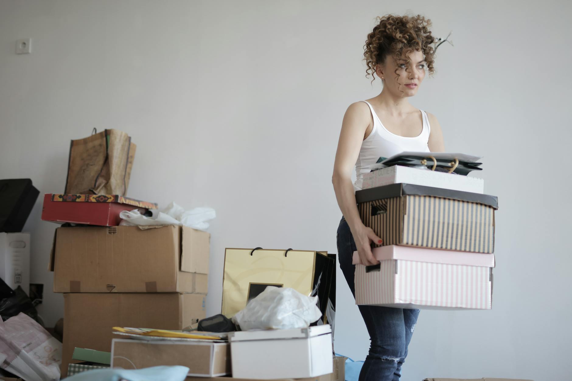 fashion-designer-34 concentrated woman carrying stack of cardboard boxes for relocation